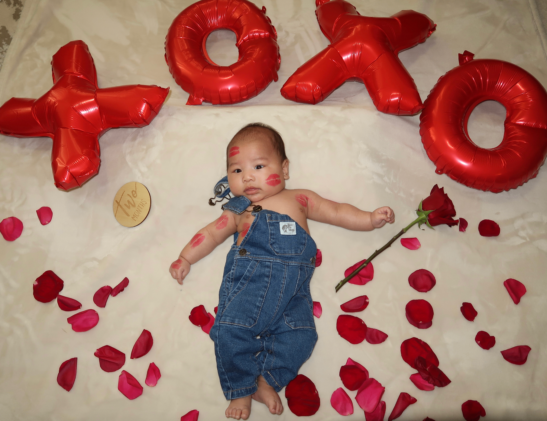 Grandbaby covered in lipstick kisses with XOXO balloons
